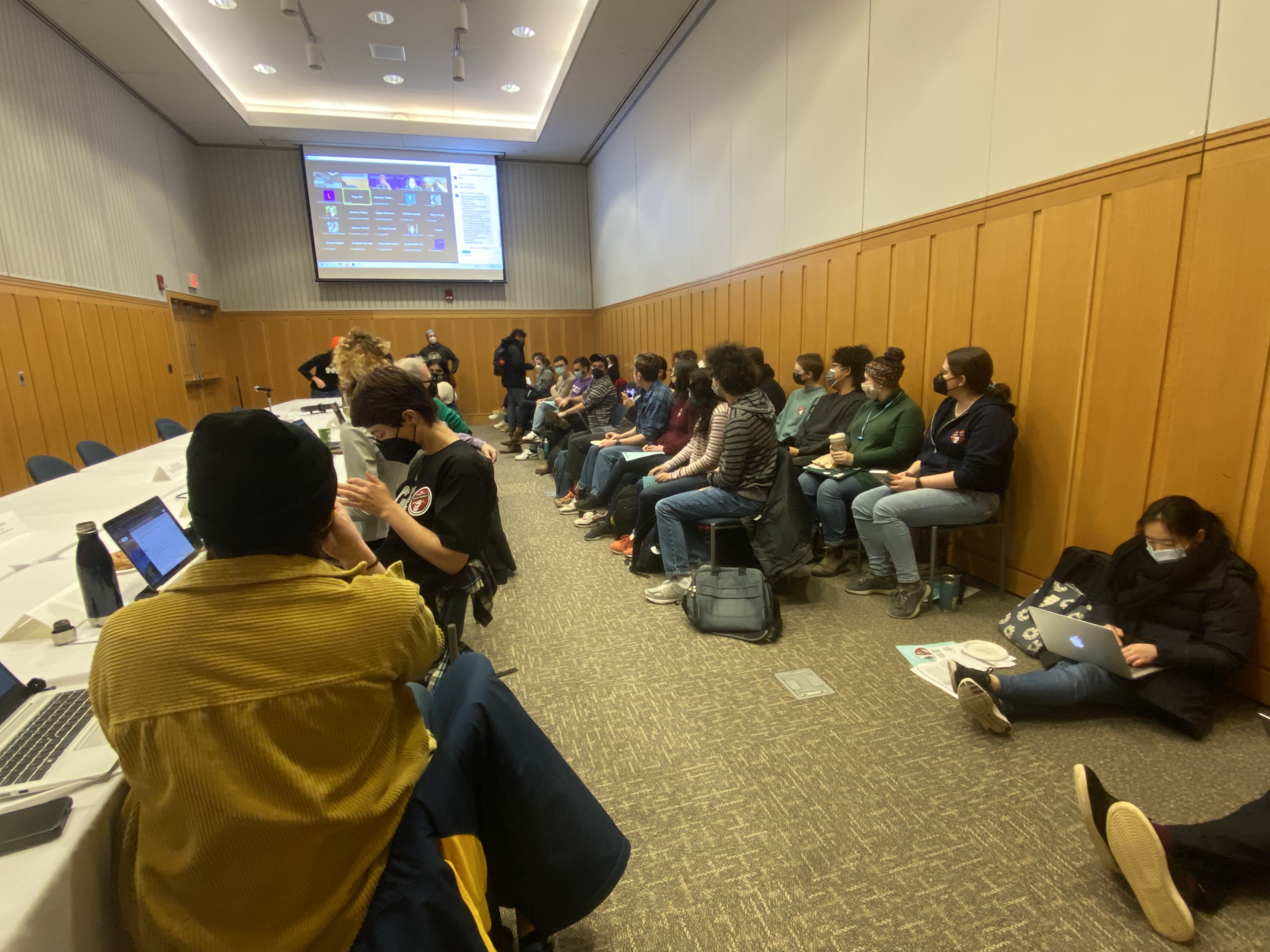 GEO members sitting in chairs and on the ground, packing a small bargaining room