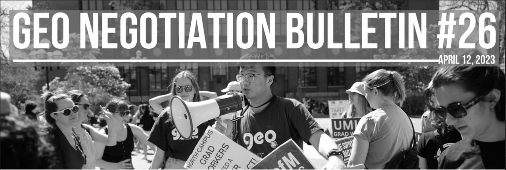A greyscale photo of a crowd with a person holding picket signs and a megaphone centered