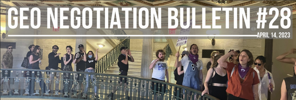 A group of people inside a building chanting and walking around a ledge with a guard rail