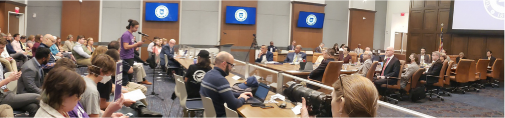 A wide shot of public speakers on the left and the Board of Regents on the right