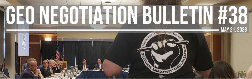 A worker wearing a GEO shirt facing a boardroom of administrators
