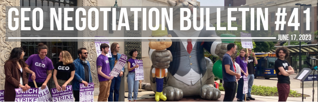 A group of workers in GEO shirts with Strike signs with Fat Cat in the background